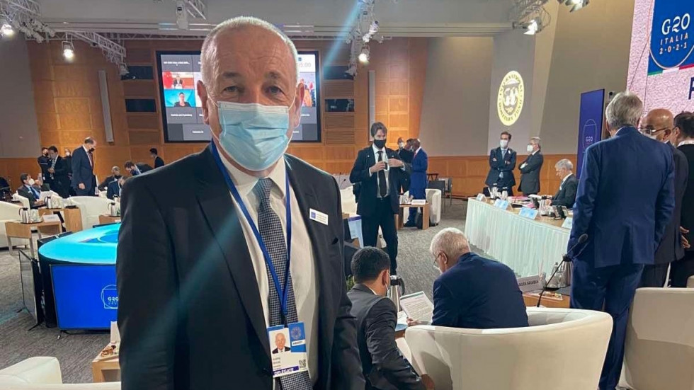 Minister Šircelj stoji v kongresni dvorani, v kateri poteka srečanje G20. V ozadju mize in ostali udeleženci srečanja.