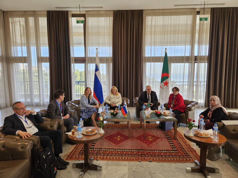 Slovenian and Algerian delegations in armchairs, with both flags in the background