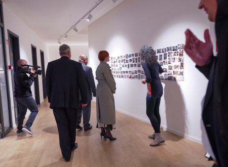 Ministrica za kulturo si ogleduje razstavljene fotografije na notranji steni kulturnega doma