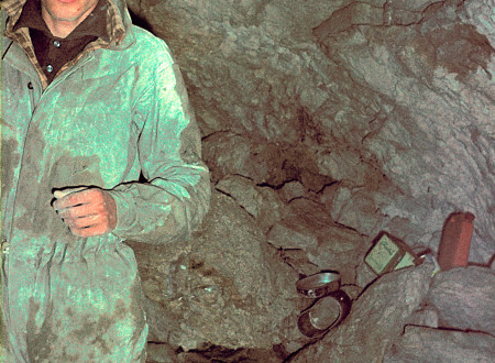 Rado Smerdu stoji pred jamsko steno, na tleh raziskovalni pripomočki