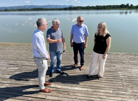 minister in predstavniki hidroelektrarne stojijo ob akumulacijskem jezeru