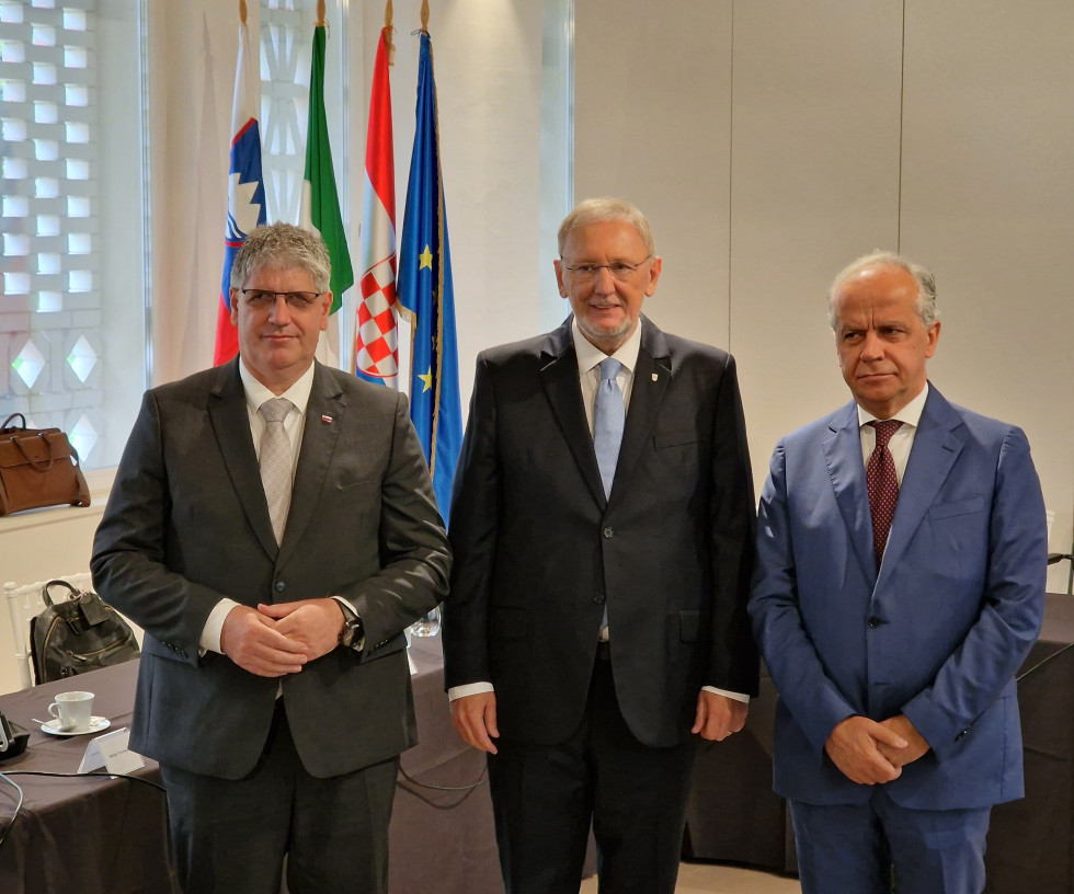 Ministers standing, behind them next to a wall slovenian, Italian, Croatian and European flags