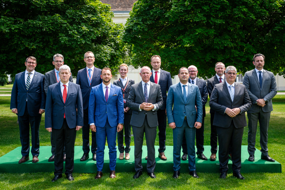 The ministers stand side by side in two rows on the grass, with trees behind them.
