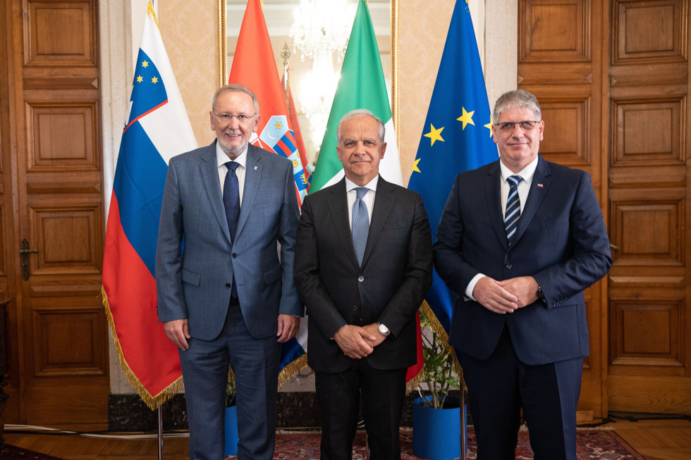 Trije ministri stojijo pred zastavami Slovenije, Hrvaške, Italije in Evropske unije. 