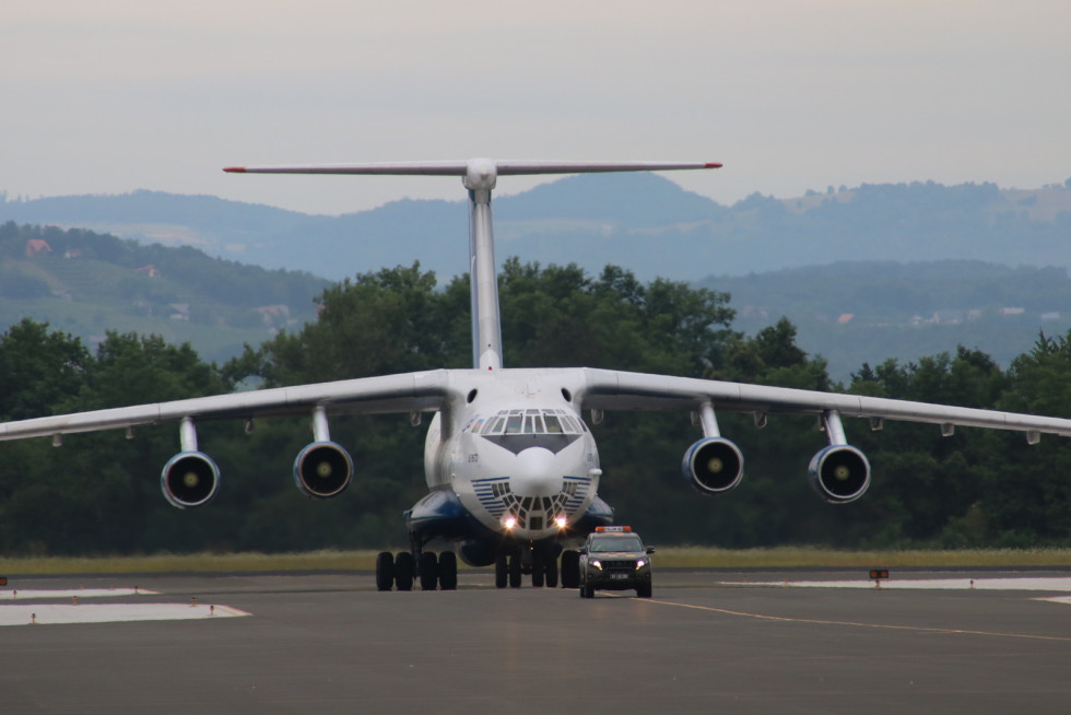 Letalo Iljušin Il-76TD na letališki stezi v Cerkljah sledi letališkemu vozilu