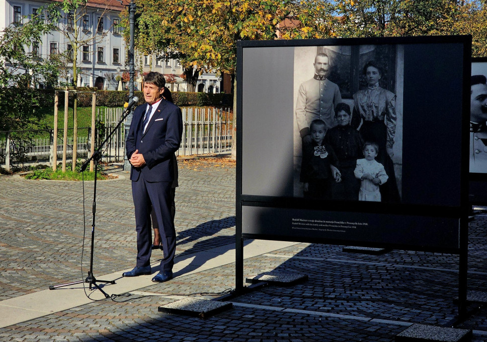 Minister med govorom stoji za mikrofonom. Ob njem je razstavni pano, za njim pa nabrežje Ljubljanice