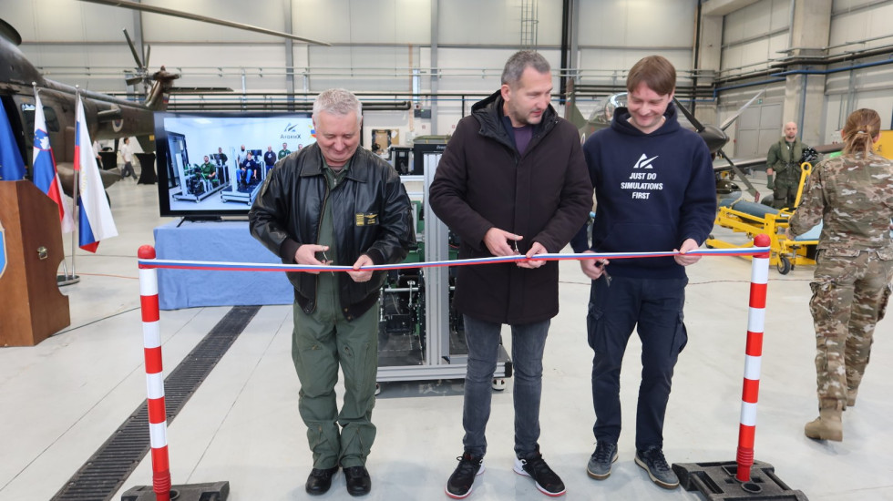 Sekretar, poveljnik brigade in predstavnik razvojnega podjetja simbolično režejo trak ob prevzemu simulatorja