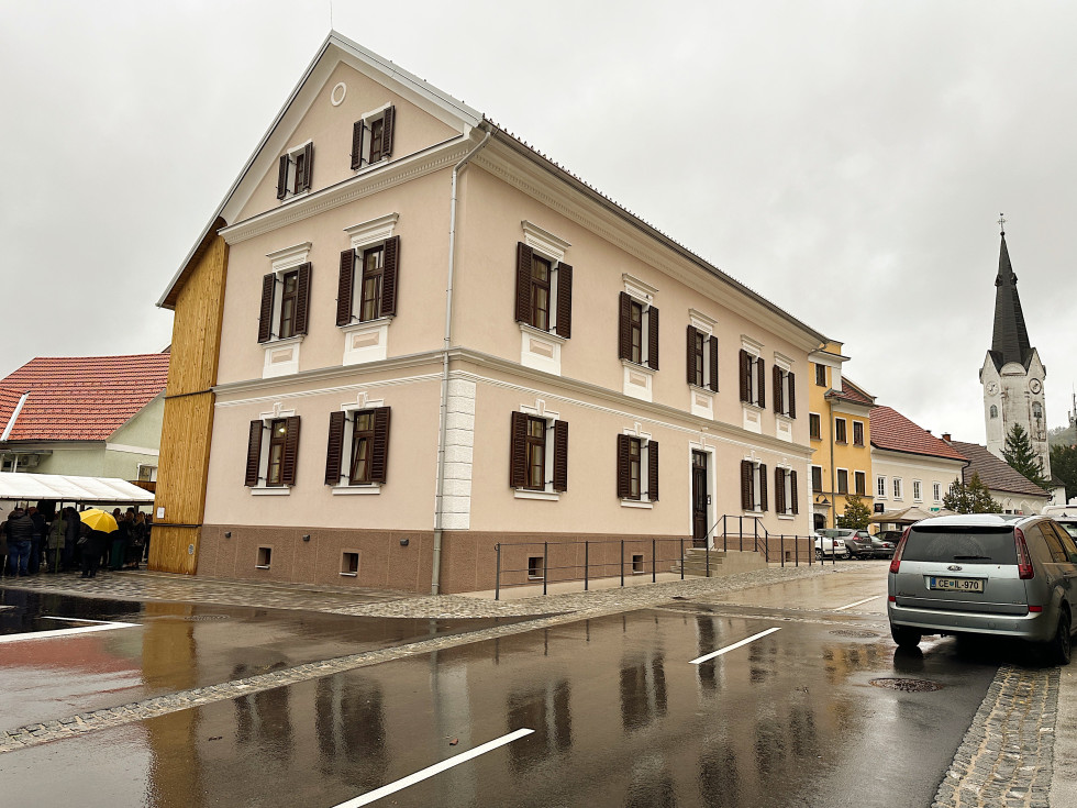 Na fotografiji stavba, v ozadju desno cerkev z zvonikom