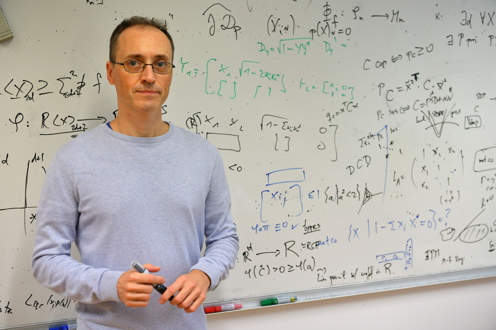 Portrait photo of dr. Igor Klep in front of a blackboard with mathematical equations.