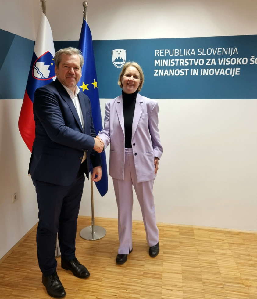 Rokovanje ministra in veleposlanice, v ozadju slovenska in evropska zastava.