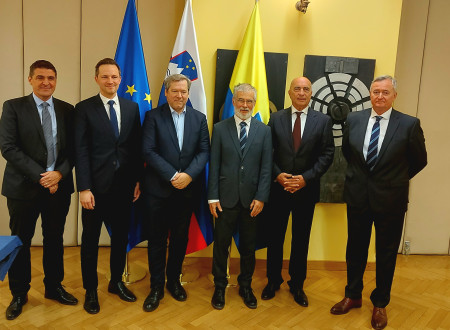 Skupinska fotografija udeležencev podpisa in novinarske konference, v ozadju evropska, slovenska in celjska zastava.