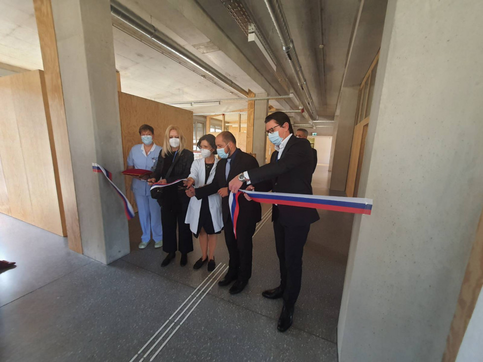 Minister Janez Poklukar in zaposleni na kliniki režejo trak ob otvoritvi novih prostorov 
