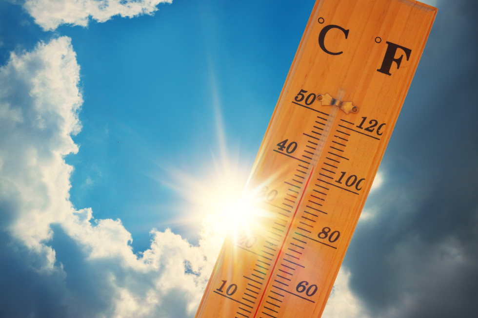 simbolna slika, lesen termometer, s prikazom temperature pri 40 stopinjah Celzija, za njim modro nebo z nekaj oblaki in sijoče sonce