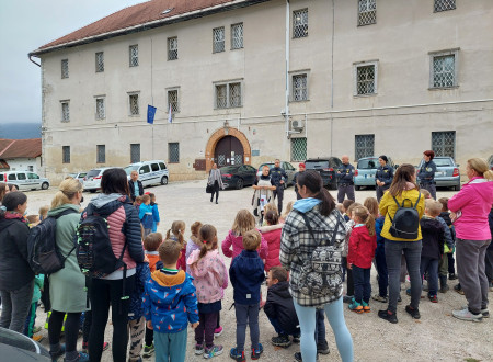 Skupina otrok z vzgojiteljicami in zaposleni na dvorišču pred ženskim zaporom