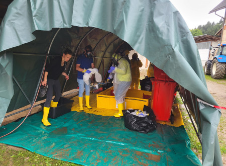 Udeleženci si razkužujejo obutev v pokritem šotoru