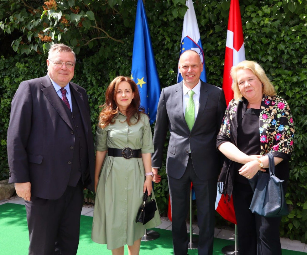 štirje ljudje stojijo pred evropsko, slovensko in dansko zastavo na vrtu