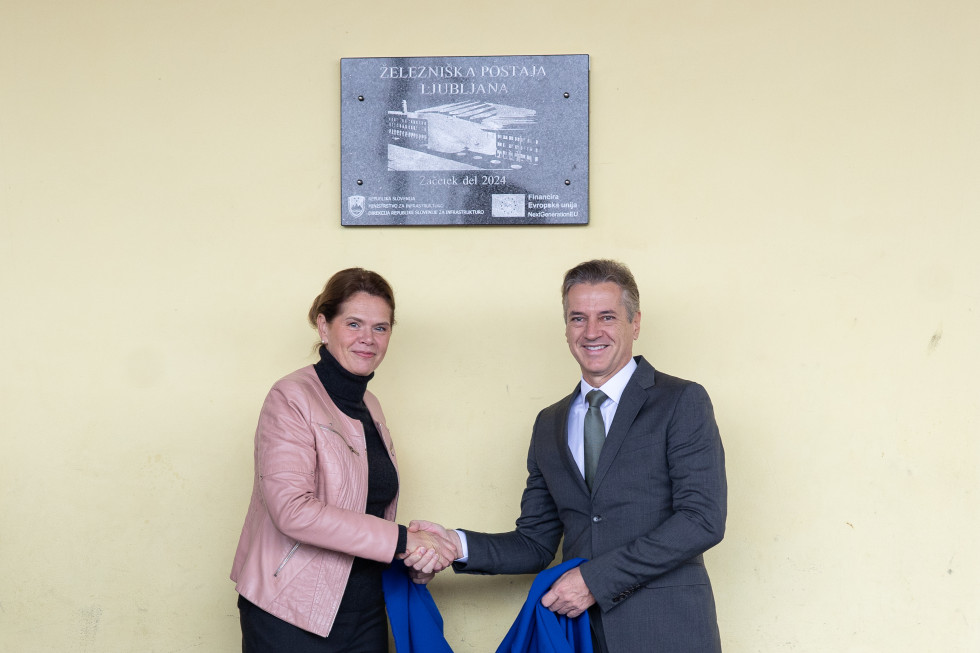 The Prime Minister and the Minister of Infrastructure shake hands under the commemorative plaque, which shows the year 2024 of the start of work and a picture of the new railway station