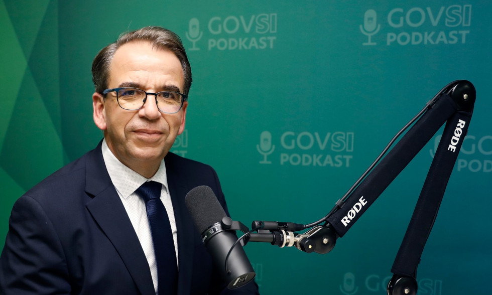 Man at microphone looking at camera and smiling, green background