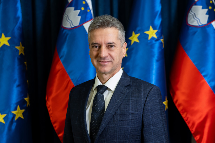 Predsednik vlade stoji, zadaj slovenska in evropska zastava