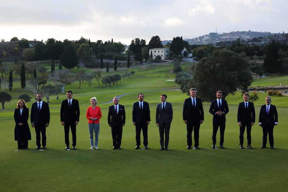 Family photo of EU heads of state in MED9 format. Eleven people are standing in a row on the lawn, one next to the other. A large garden and a house in the background.