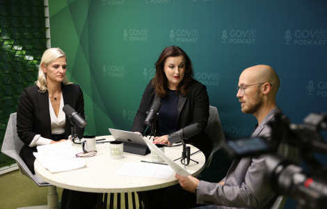 DK992331 (Two women and a man sitting at a round table and talking in a green room.obi z zelenim ozadjem in se pogovarjajo.)