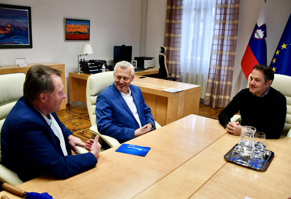 Silvo Kumer, Marko Wieser, Matej Arčon sedijo za mizo. V ozadju slovenska in evropska zastava.