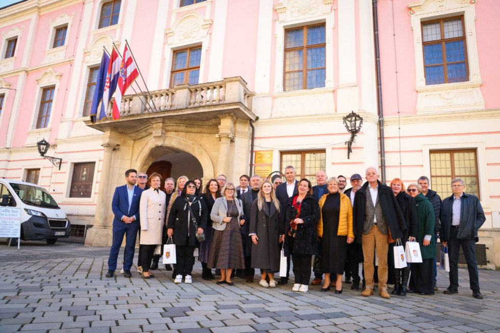 Udeleženci srečanja pred županijsko stavbo. Na balkonu zastave.