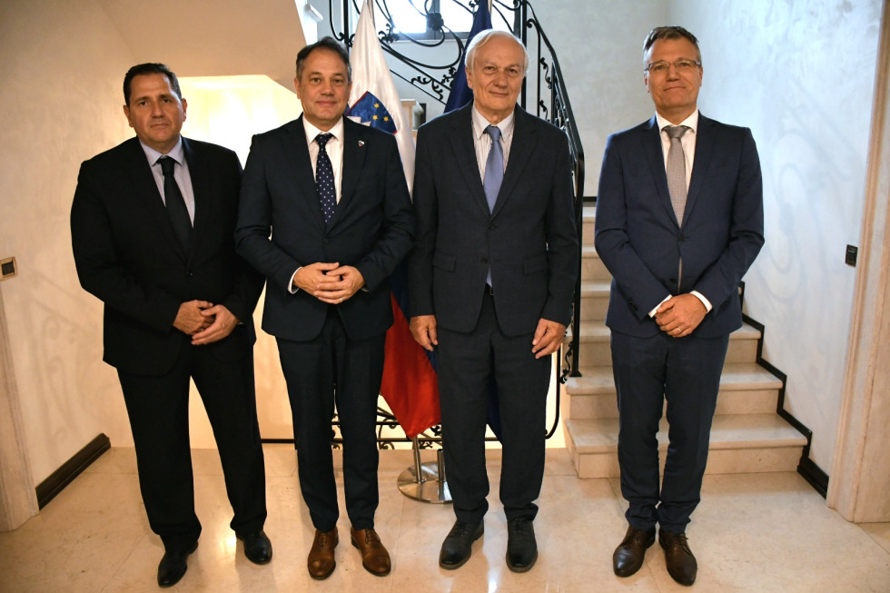Častni konzul Marić, miniser Arčon, predsednik Verbič, veleposlanik Bergant stojijo pred zastavami.