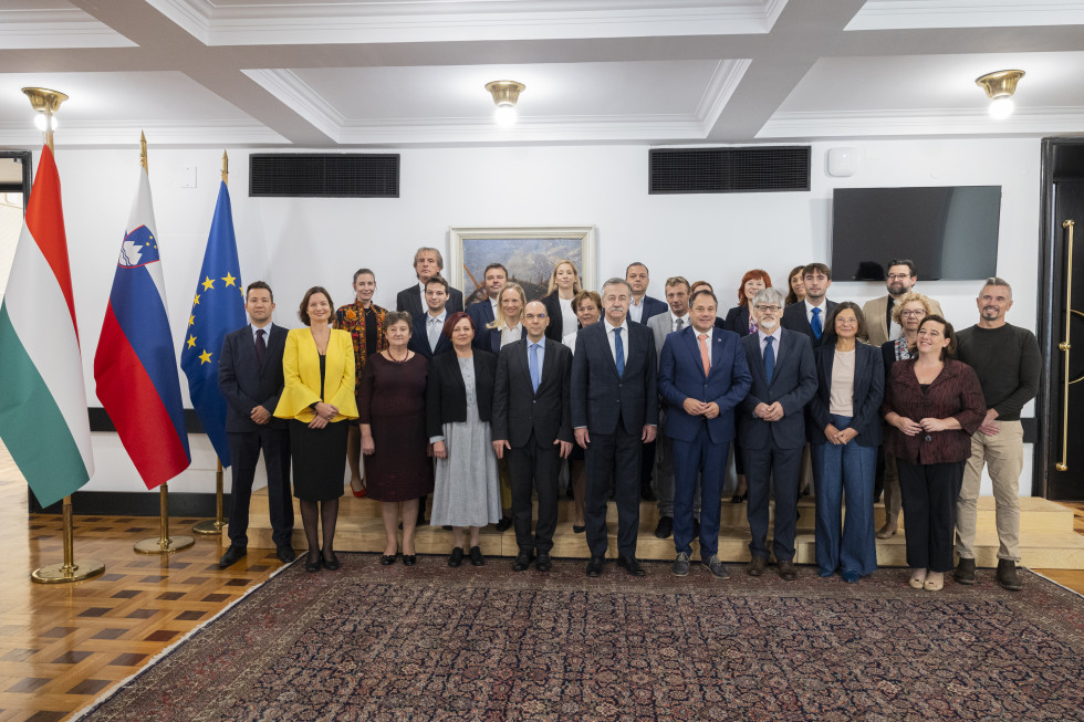 Minister Matej Arčon, ministrski komisar Ferenc Kalmar in slovenska ter madžarska delegacija. Skupinska fotografija, ob strani madžarska, slovenska in evropska zastava. 