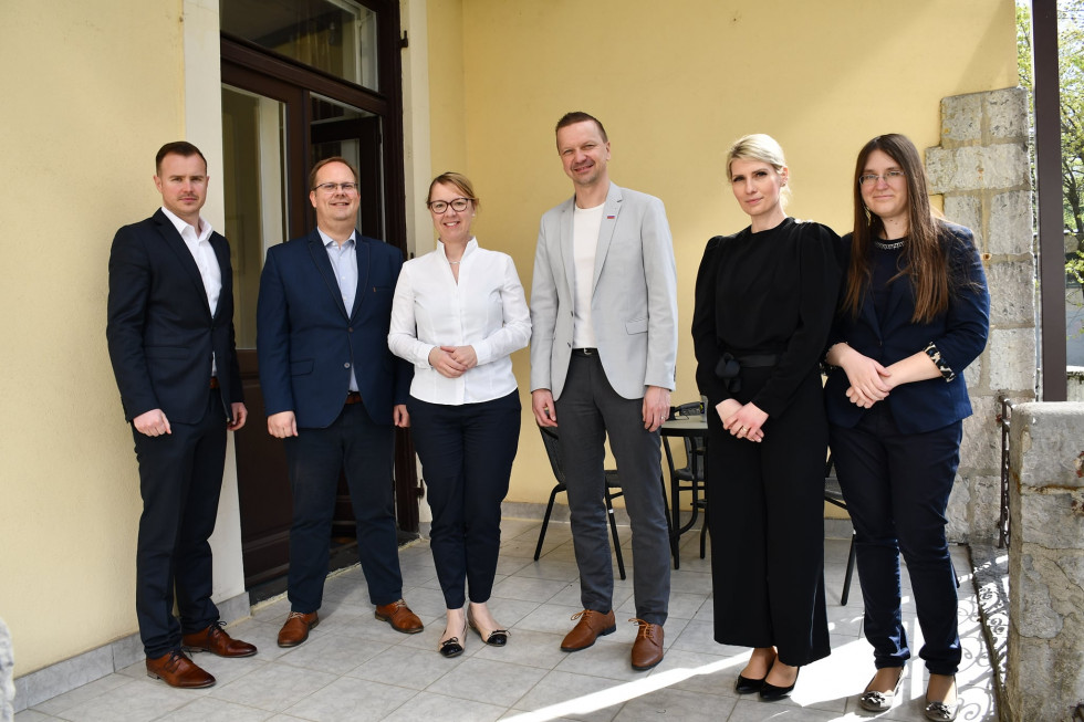 Helena Jaklitsch, Danilo Lončarič in drugi stojijo pred vhodom v Urad za zamejce po svetu.